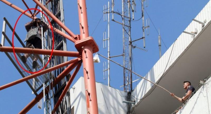 Distraught man sitting atop tower at Bangkok police HQ