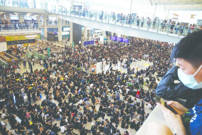  
Anti-extradition-bill protesters, clad in black shirts, pack an arrival hall of Hong Kong International Airport on Friday. (CHINA DAILY)