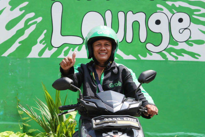 A GrabBike driver smiles as he greets his customer. Sofbank announced on Monday another US$2 billion investment for the Indonesian operation of the Singapore-based ride hailing company. (Photo Courtesy of JP/ Arief Suhardiman )