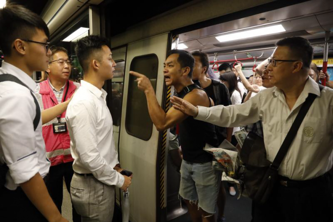 Commuters argue angrily with protesters who tried to prevent train door from closing at MTR Fortress Hill station early Monday morning. (PHOTO / CHINA DAILY)