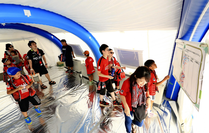 People walk through a tent-like covered passage that is cooled by an air-conditioning system using snow in front of Saitama Stadium in Saitama./The Japan News Photo