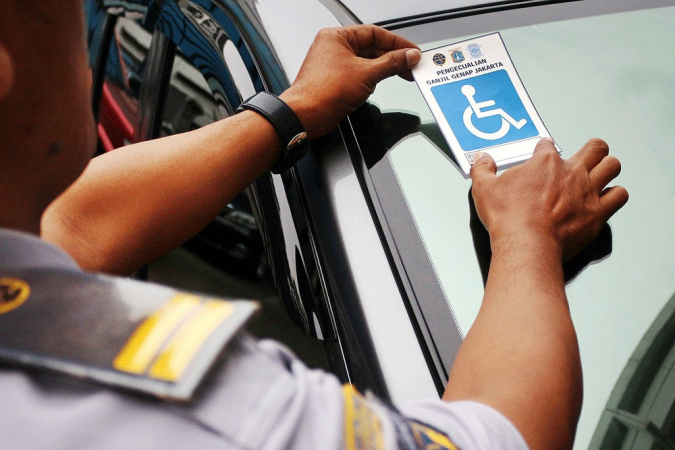 Waiver: A Jakarta Transportation Agency official affixes a disability sticker to a car parked at the agency’s office in Central Jakarta on Tuesday that exempts the driver from the odd-even license plate traffic restriction. (The Jakarta Post/Umair Rizaludin )