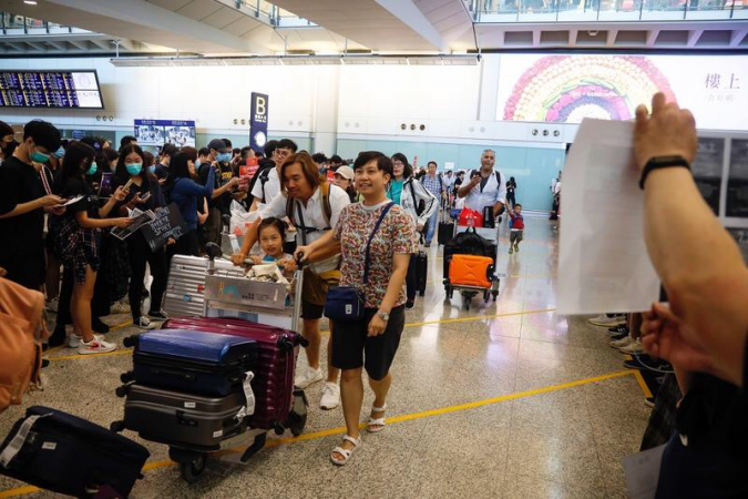 Black-clad protesters against the extradition bill hand out leaflets to arrival passengers at Hong Kong International Airport on July 26, 2019. (PHOTO / CHINA DAILY)
