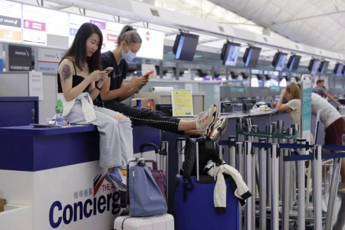 Stranded travellers sit on the check-in counters at the Hong Kong International Airport yesterday. (Photo: AP)