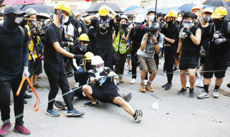 Protesters use a giant slingshot to shoot bricks and stones into Tsuen Wan Police Station on Aug 5, 2019. [Photo/China Daily]