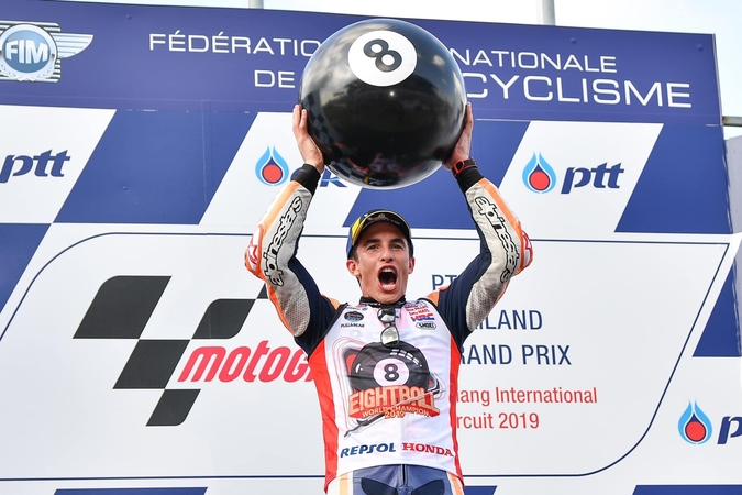 Marc Marquez holds a giant billiard ball to celebrate his eighth World Championship title.