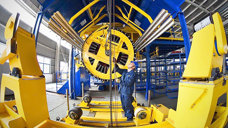 An employee installs an intelligent pipe winding machine at an industrial park in Lianyungang, Jiangsu province, on Nov 27, 2019. [Photo by Geng Yuhe/For China Daily]
