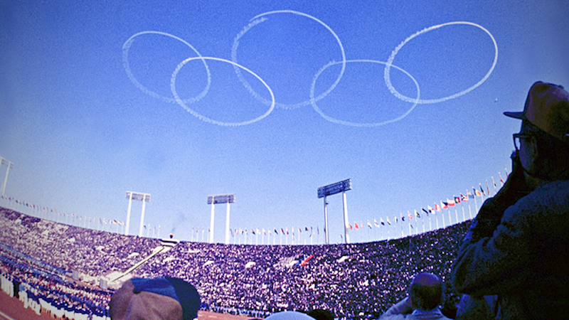 Vapor trails from jets flown by Blue Impulse, the Air Self-Defense Force's acrobatic squadron, form the Olympic logo over the old National Stadium at the 1964 Tokyo Games. MUST CREDIT: Japan News-Yomiuri file photo
