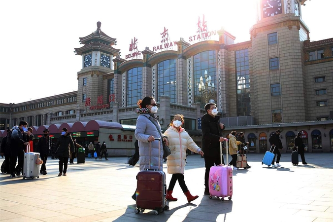Passengers wearing face masks arrive at the Beijing Railway Station in Beijing on Jan 30, 2020. [Photo by Zou Hong/China Daily]
