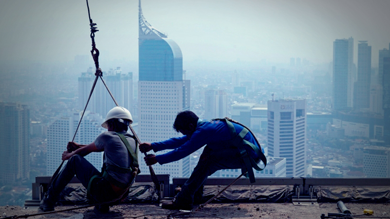 Construction workers labor on a building towering above the business district in Jakarta, Indonesia. MUST CREDIT: Bloomberg photo by Dimas Ardian