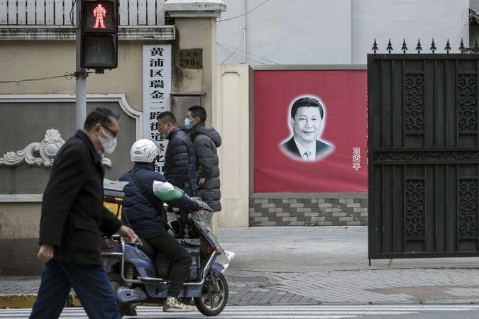 Pedestrians wearing protective masks and a motorcyclist pass a banner featuring a photograph of Chinese president Xi Jinping in Shanghai on March 2, 2020. MUST CREDIT: Bloomberg photo by Qilai Shen.