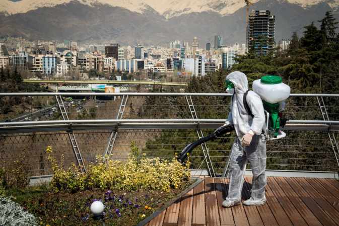 A firefighter in protective clothing sprays disinfectant on a pedestrian overpass in Tehran on March 9, 2020. MUST CREDIT: Bloomberg photo by Ali Mohammadi.
