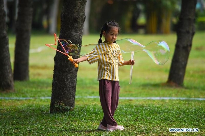 A child plays bubbles at Evergreen Park in Haikou, south China's Hainan province, March 19, 2020. (PU XIAOXU / XINHUA)