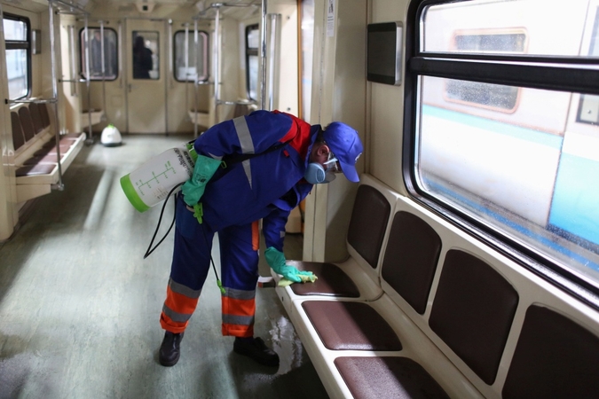 A worker wearing a protective face mask and gloves wipes down seating inside a passenger train on the Moscow Metro in Moscow on March 25, 2020. MUST CREDIT: Bloomberg photo by Andrey Rudakov.