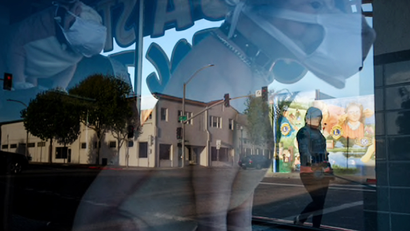A person walks by a storefront display of dog mannequins wearing masks in Lompoc, Calif. MUST CREDIT: photo for The Washington Post by Karla Gachet.