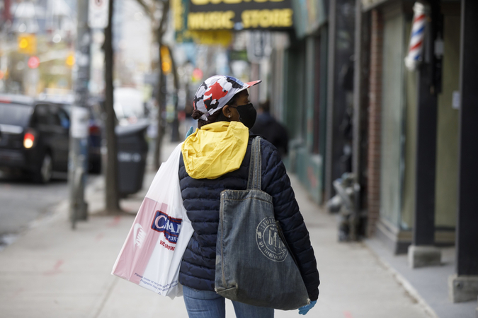 A pedestrian wearing a protective mask carries shopping bags in Toronto on May 19, 2020. MUST CREDIT: Bloomberg photo by Cole Burston.