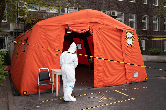A medical worker stands beside a tent set up for visitor temperature checks outside the Czerniakowski Hospital in Warsaw, Poland, on April 29. 2020. MUST CREDIT: Bloomberg photo by Agata Grzybowska.
