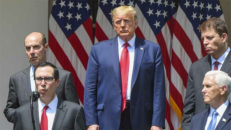 President Donald Trump, Vice President Mike Pence and other aides listen as Treasury Secretary Steven Mnuchin speaks in the Rose Garden of the White House on Friday. MUST CREDIT: Washington Post photo by Jonathan Newton