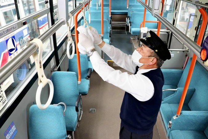 Local bus operators, one of the hard-hit businesses due to school closures during the coronavirus outbreak, cleans a bus in Ibaraki.