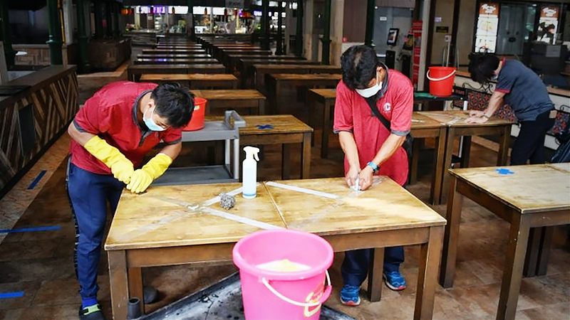 Cleaners removing masking tapes from tables at Lau Pa Sat on June 15, 2020. ST PHOTO: CHONG JUN LIANG