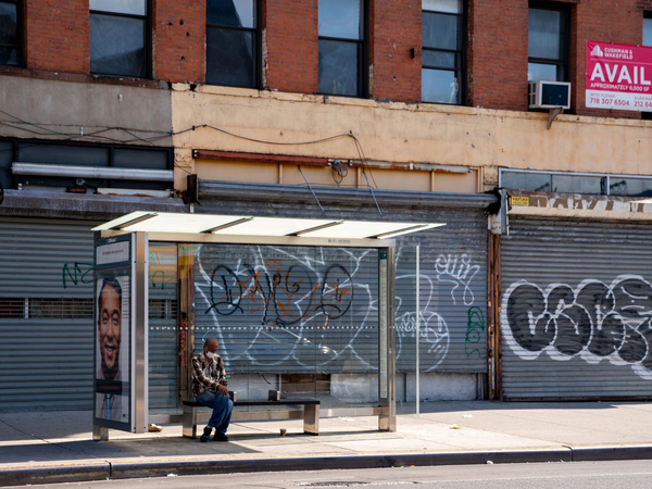 A person sits at a bus stop next to closed businesses in the New York borough of Brooklyn on June 17, 2020. MUST CREDIT: Bloomberg photo by David Dee Delgado.
