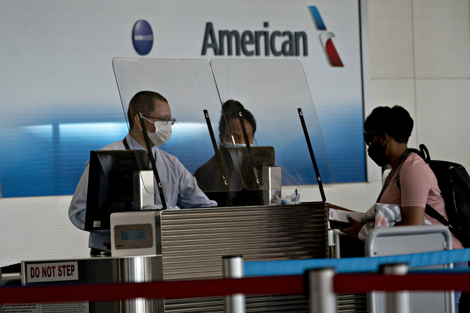American Airlines employees wear take coronavirus precautions while checking in a traveler in June 2020. MUST CREDIT: Washington Post photo by Andrew Harrer
