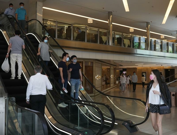People wearing face masks ride an escalator in a shopping mall in Central, Hong Kong, July 22, 2020. (CALVIN NG / CHINA DAILY)
