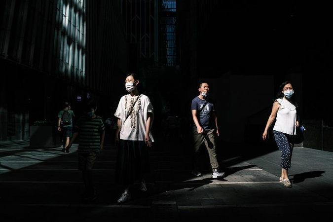 Pedestrians walk in an alleyway between commercial buildings in Hong Kong on July 22, 2020. (ANTHONY WALLACE / AFP)