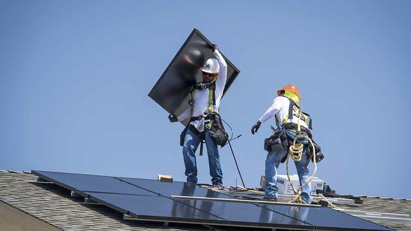 Contractors install solar panels on the roof of a new home in Sacramento, California, on Aug. 15, 2018. MUST CREDIT: Bloomberg photo by David Paul Morris.