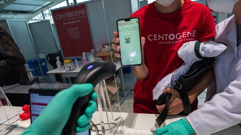 An employee holds a smartphone displaying a quick response (QR) code to register for a polymerase chain reaction (PCR) swab test at a covid-19 test center at Frankfurt Airport in Frankfurt, Germany, on Aug. 27, 2020. MUST CREDIT: Bloomberg photo by Alex Kraus.