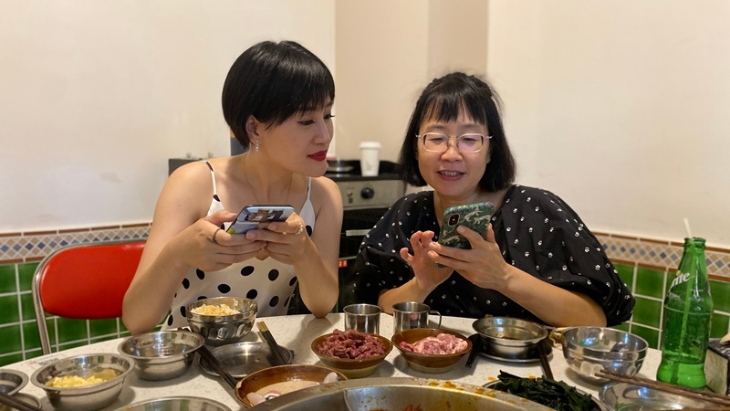 Food bloggers Li Yibing, left, and Qu Wenjie discuss their plans to promote serving utensils, instead of sharing chopsticks and potentially germs, over hot pot at a Dian Tai Xiang branch in Chengdu, China. MUST CREDIT: Washington Post photo by Anna Fifield.