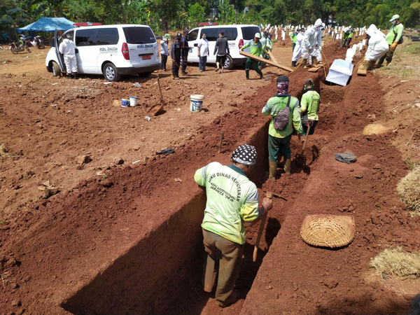 Workers dig graves while others place the body of a COVID-19 victim in a burial plot at the Pondok Ranggon public cemetery in East Java on July 27. (JP/P.J. Leo)