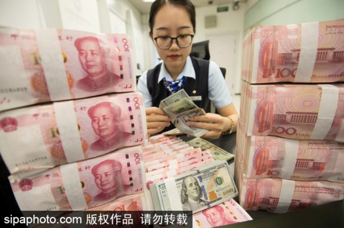 A cashier counts RMB and US dollar notes in a bank in Nantong, Jiangsu province, on Aug 6, 2019. [Photo/Sipa]