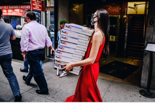 A pedestrian wearing a protective mask carries FedEx boxes in the Diamond District of New York on June 10, 2020. MUST CREDIT: Bloomberg photo by Nina Westervelt.