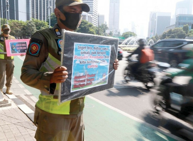 Jakarta Public Order Agency (Satpol PP) officers carry posters calling on residents to comply with government-imposed health protocols during rush hour in Senayan, South Jakarta, on Monday. (JP/Dhoni Setiawan)