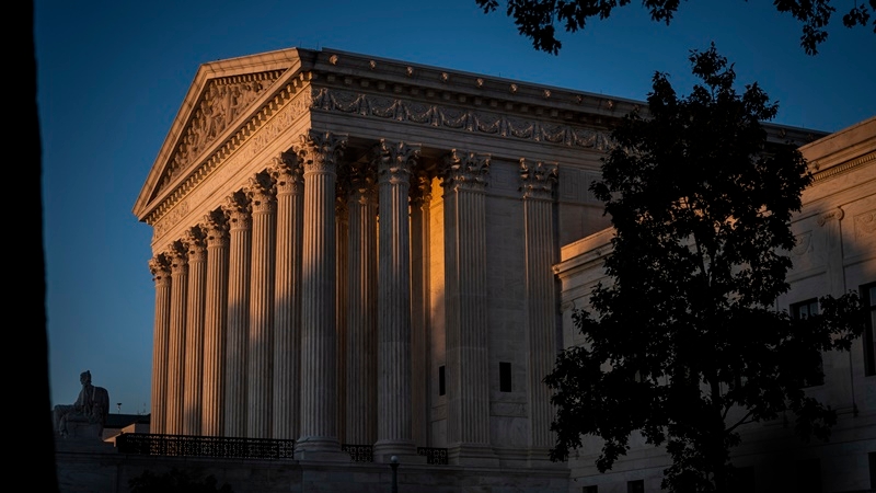 The sun sets as people gather to pay respects to Justice Ruth Bader Ginsburg in front of the Supreme Court Monday. MUST CREDIT: Washington Post photo by Jabin Botsford