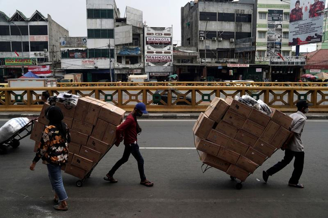 Workers transport carts loaded with boxes at Tanah Abang market in Jakarta, Indonesia, on Aug 4, 2020. (PHOTO / BLOOMBERG)