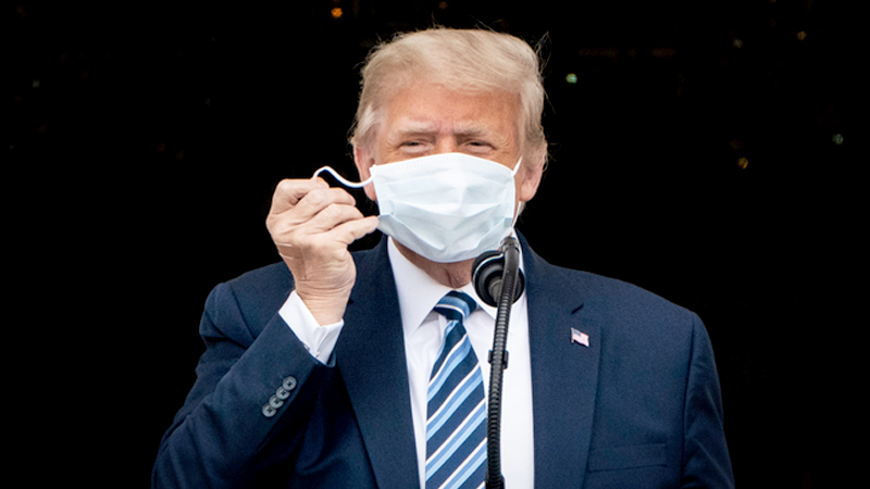 President Donald Trump removes his mask as he arrives to speak to supporters at the White House on Saturday, Oct. 10, 2020. MUST CREDIT: Washington Post photo by Jabin Botsford