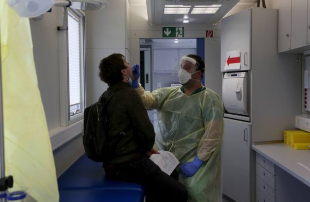 A health worker administers a covid-19 swab test on a traveler who had just arrived in Berlin on Oct. 12, 2020. MUST CREDIT: Bloomberg photo by Liesa Johannssen-Koppitz