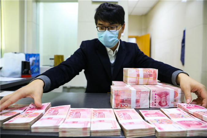 A teller counts cash at a bank branch in Hangzhou, capital of East China's Zhejiang province. [Photo by Hu Jianhuan/For China Daily]
