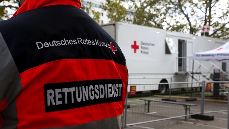 A member of Germany's Red Cross stands near a Covid-19 mobile testing unit as travelers are tested in Berlin, Germany, on Oct. 12, 2020. MUST CREDIT: Bloomberg photo by Liesa Johannssen-Koppitz.