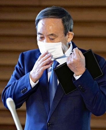 Prime Minister Yoshihide Suga takes off his mask to answer questions from reporters at his office on Thursday. (The Yomiuri Shimbun)