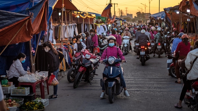 Motorcyclists pass customers shopping at a makeshift market set up near the Foxconn factory in Viet Yen district, Bac Giang province, Vietnam, on Oct. 10, 2020. MUST CREDIT: Bloomberg photo by Linh Pham.