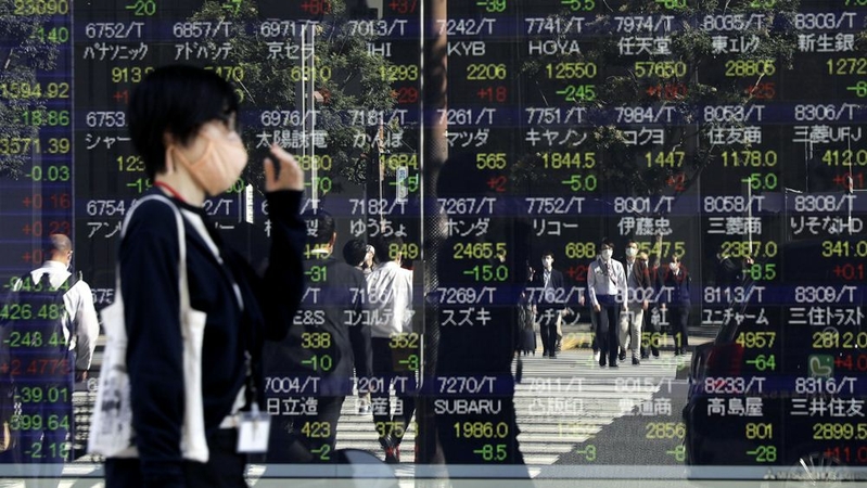 Pedestrians reflected in an electronic stock board outside a securities firm in Tokyo on Oct. 29, 2020. MUST CREDIT: Bloomberg photo by Kiyoshi Ota.