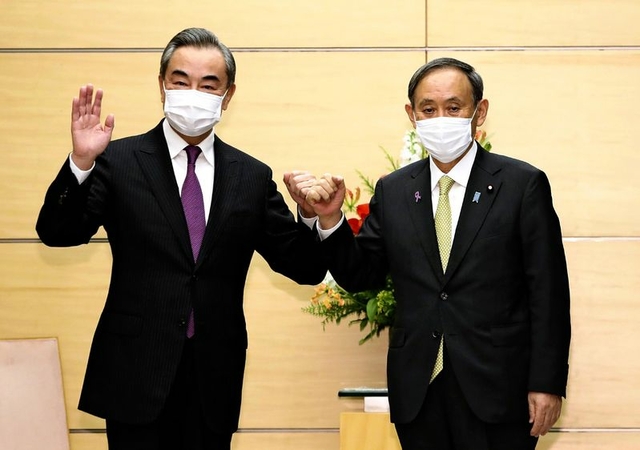 Prime Minister Yoshihide Suga, right, and Chinese Foreign Minister Wang Yi pose before a meeting at the Prime Minister’s Office on Wednesday. (The Yomiuri Shimbun)