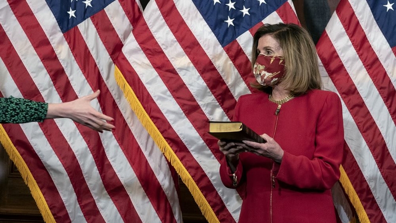 A staff member gives House Speaker Nancy Pelosi, a Democrat from California, a Bible during a ceremonial swearing-in of Rep. Kwanza Hall, D-Ga., not pictured, at the U.S. Capitol in Washington, D.C. on Dec. 3, 2020. MUST CREDIT: Bloomberg photo by Stefani Reynolds.