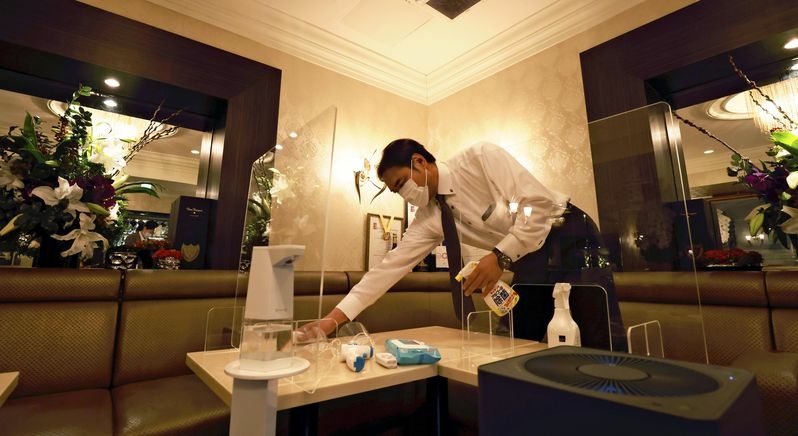 An employee sanitizes a table at a bar in Chuo Ward, Tokyo, earlier this month. (The Yomiuri Shimbun)