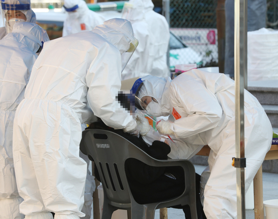 
A medical worker collects a specimen from a student at a screening station in Ulsan, 414 kilometers southeast of Seoul, for COVID-19 testing on Saturday. (Yonhap)