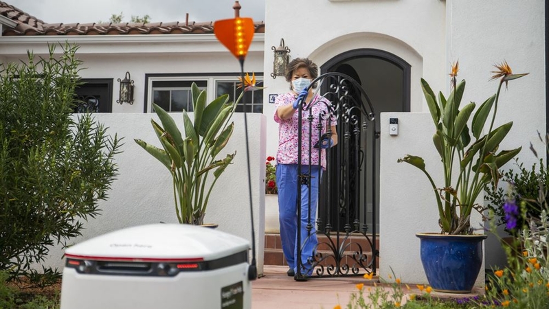 A healthcare worker receives groceries delivered with a Starship Technologies robot in Mountain View, California, on May 18. MUST CREDIT: Bloomberg photo by Nina Riggio.