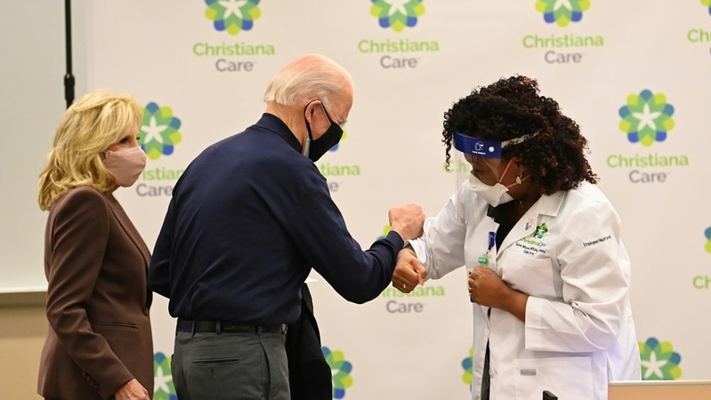 Nurse practitioner Tabe Mase congratulates President-elect Joe Biden after administering his first dose of the coronavirus vaccine Monday in Delaware. MUST CREDIT: Washington Post photo by Jonathan Newton.